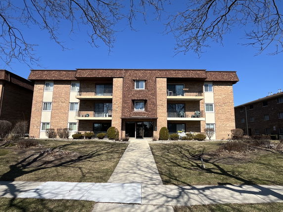 Front view of a multi-story brick apartment building with balconies.