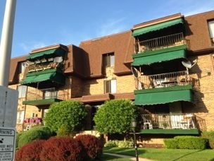 Front view of a three-story brick apartment building with green awnings.