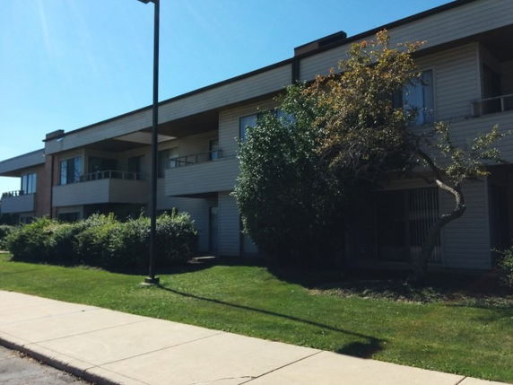 Front view of a two-story building with balconies and large windows.