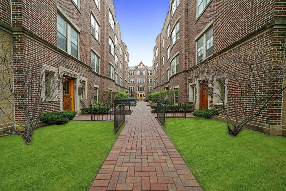 Front view of a brick apartment complex with a central walkway.