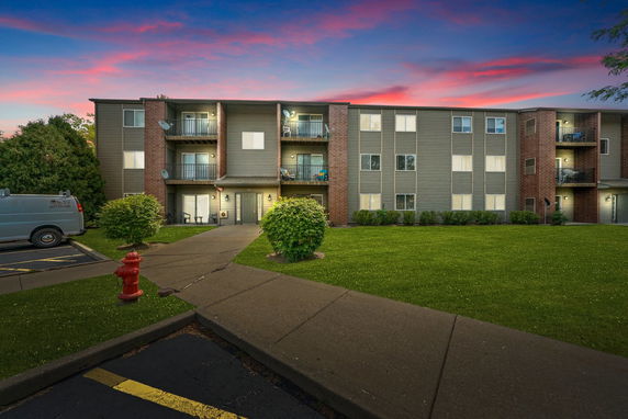 Front view of a three-story apartment building with balconies and brick accents.