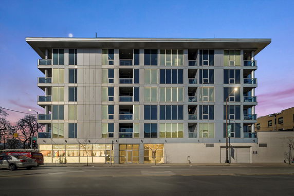 Front view of a multi-story building with balconies and large windows.