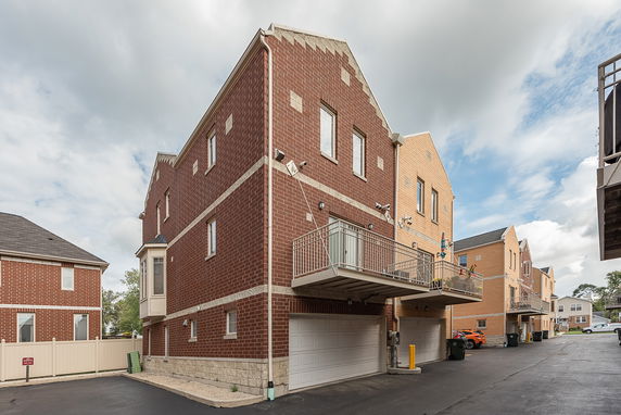 Side view of a multi-story brick building with garages and balconies.