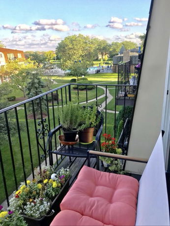 Balcony view overlooking a garden and adjacent buildings.