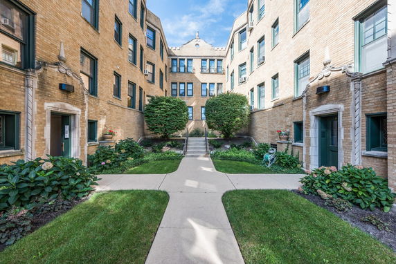Front view of a multi-story apartment building with a courtyard entrance.