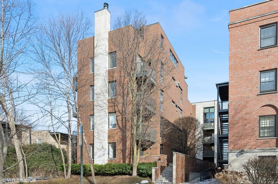 Front view of a multi-story brick apartment building with large windows.