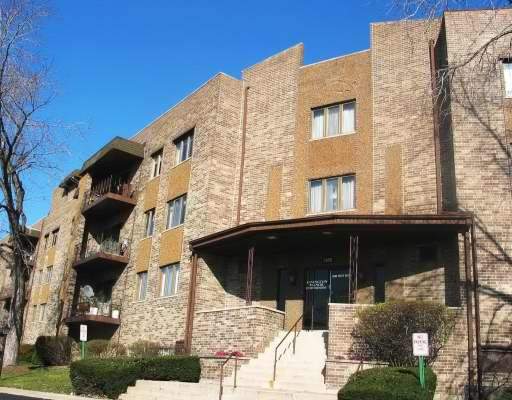Front view of a multi-story brick apartment building with balconies.