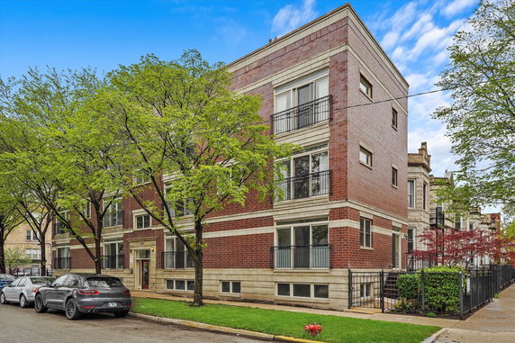 Front view of a three-story brick building with balconies.