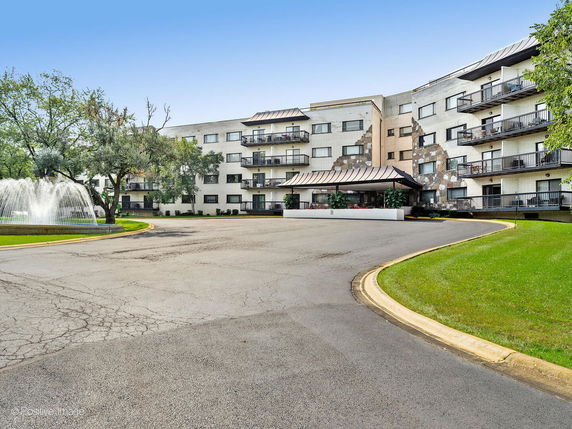 Front view of a multi-story building with balconies and a circular driveway.