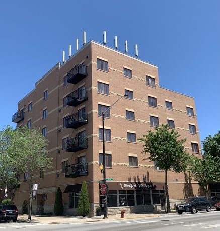 Front view of a multi-story brick building with small balconies.