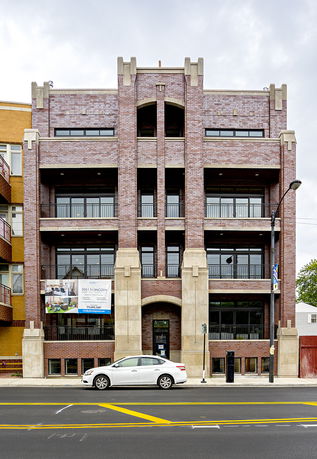 Front view of a multi-story brick building with balconies.