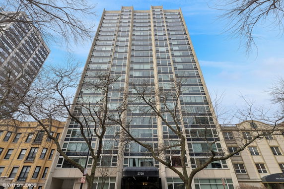 Front view of a tall apartment building with large windows.