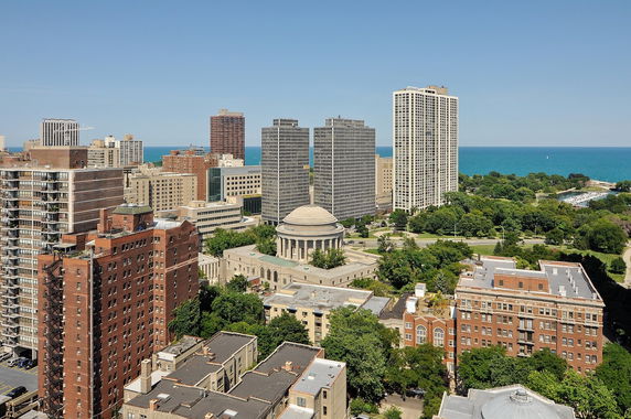 Panoramic view of a cityscape with multiple buildings and a lake in the background.