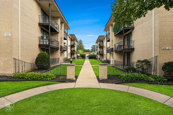 Front view of two multi-story apartment buildings with balconies and a central walkway.