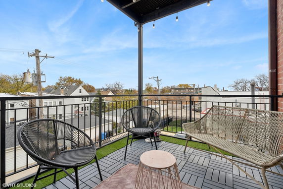 Balcony view showing outdoor seating and overlooking nearby houses and trees.