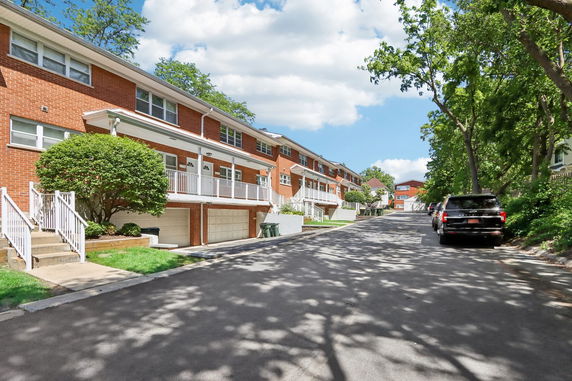 Front view of a row of two-story brick townhouses with garages.
