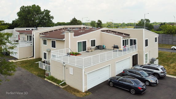 Front view of a two-story residential building with multiple garages and a rooftop terrace.