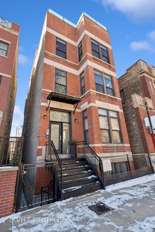Front view of a multi-story brick building with a small staircase leading to the entrance.