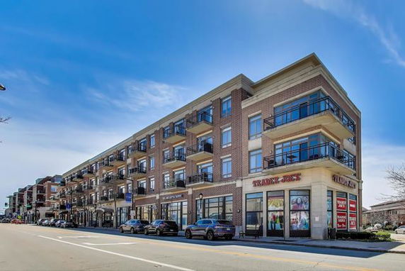 Front view of a multi-story building with street-level shops and upper-floor balconies.