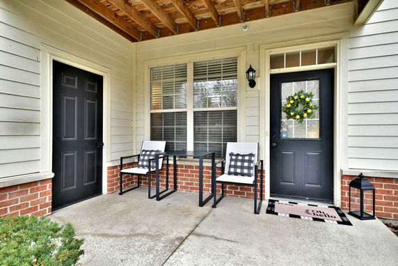 Front view of a house with a porch, featuring two chairs and a table.