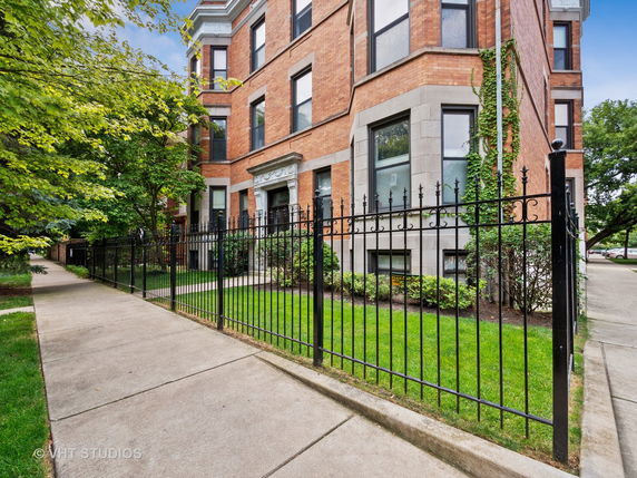 Front view of a multi-story brick building with wrought iron fence.