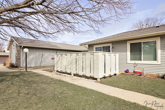 Front view of a single-story house with a fenced area and large windows.