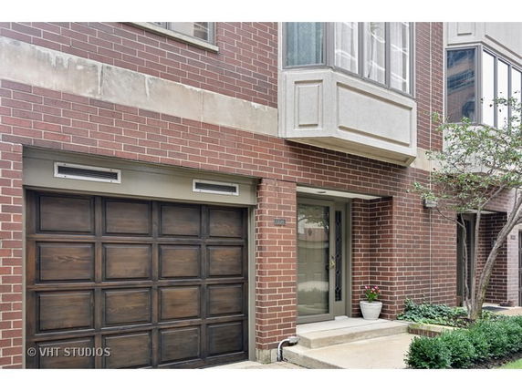 Front view of a brick townhouse with a garage and bay window.
