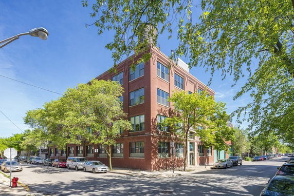 Front view of a multi-story brick building on a street corner.