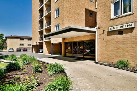Front view of a multi-story brick building with parking area and entrance canopy.
