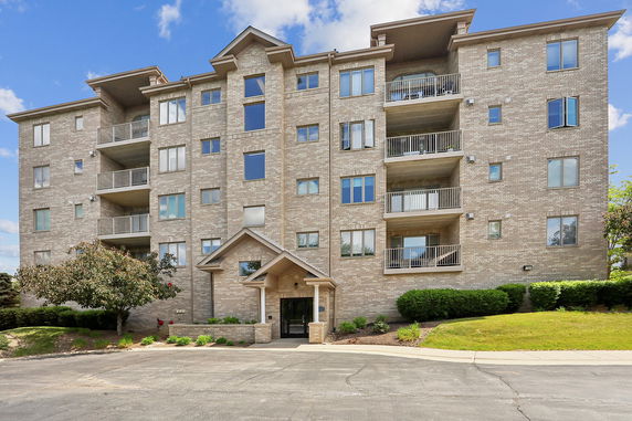 Front view of a multi-story apartment building with balconies and a central entrance.