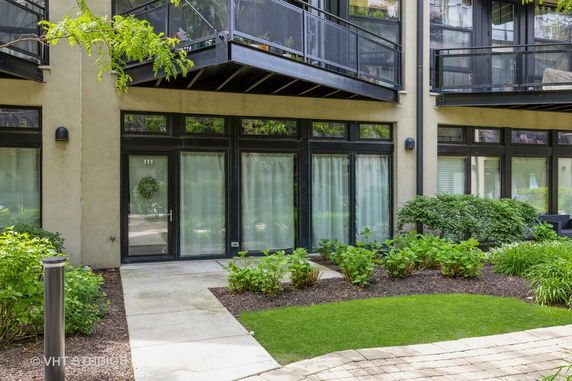Front view of a modern apartment building with balconies and landscaped garden.