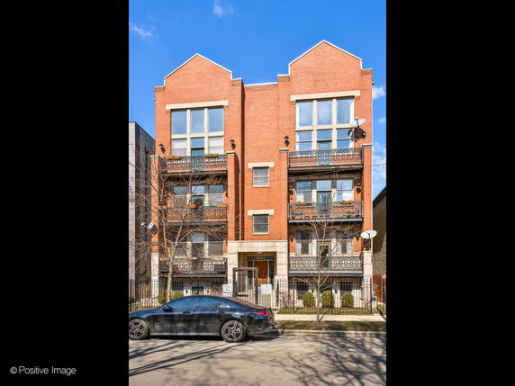 Front view of a multi-story brick residential building with balconies.