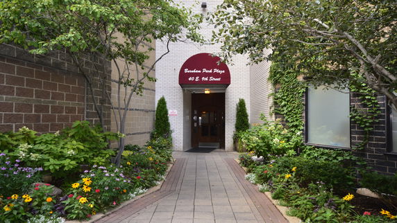 Entrance to a building with a red awning and surrounding greenery.