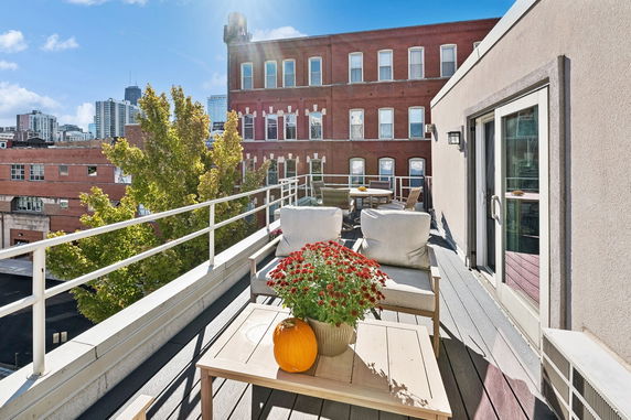 Rooftop seating area with chairs and a table, overlooking a cityscape.