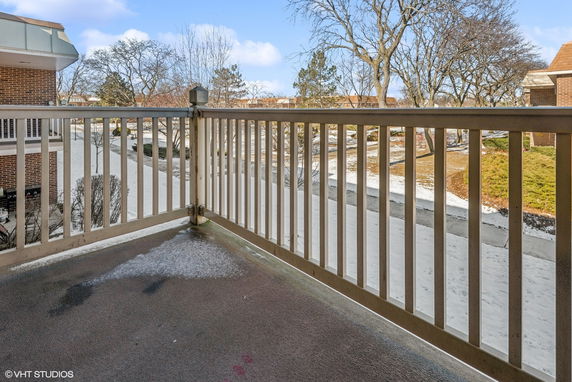 View from a balcony overlooking a snowy outdoor area with trees and buildings.