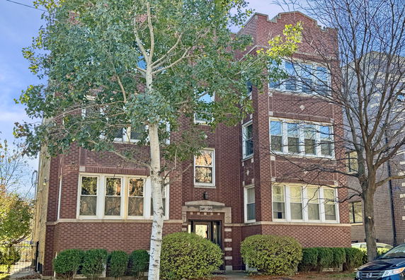 Front view of a multi-story brick building with multiple windows and a central entrance.