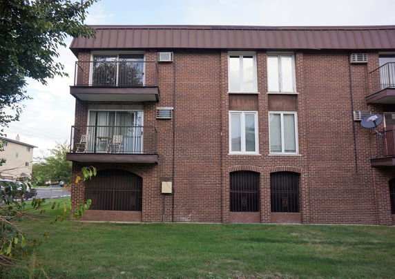 Front view of a brick three-story building with balconies and large windows.