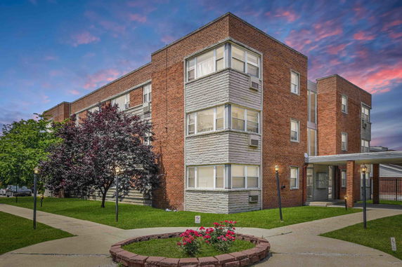 Front view of a three-story brick apartment building with multiple windows.