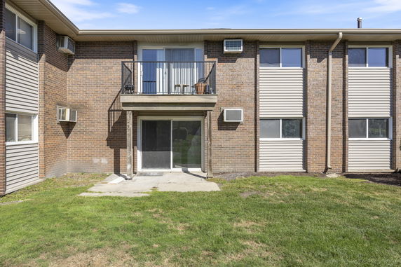Front view of a two-story brick building with a balcony and sliding glass doors on the ground floor.