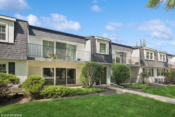 Front view of a two-story residential building with balconies and a walkway in front.