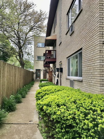 Side view of a multi-story brick building with exterior walkway and balconies.