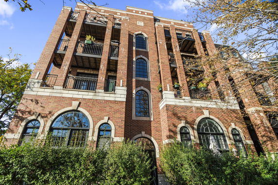 Front view of a multi-story brick building with balconies and arched windows.