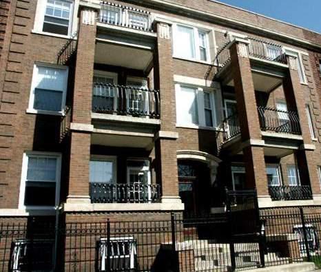 Front view of a multi-story brick apartment building with balconies.