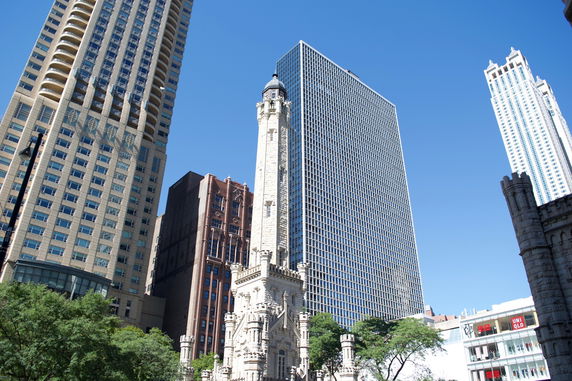 Front view of a tall historical building surrounded by modern skyscrapers.