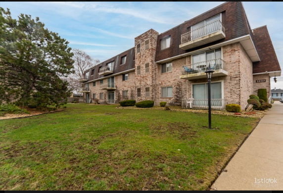 Front view of a multi-story brick residential building with balconies.