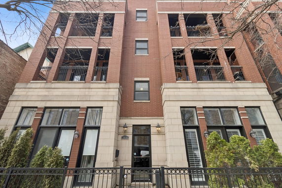 Front view of a multi-story brick building with balconies and large windows.
