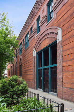 Front view of a brick building with large arched windows and a gated entrance.