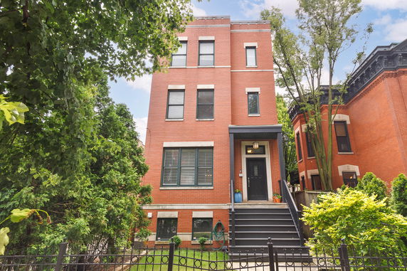 Front view of a three-story brick house with a staircase leading to the main entrance.