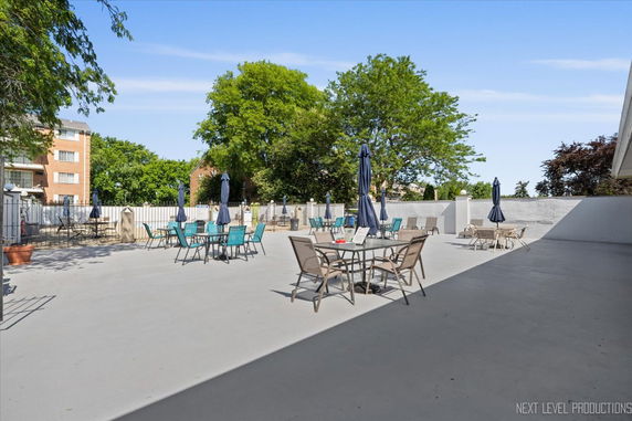 Outdoor seating area with tables and chairs near an apartment building.