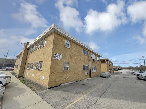 Front view of a two-story brick building with a parking area.